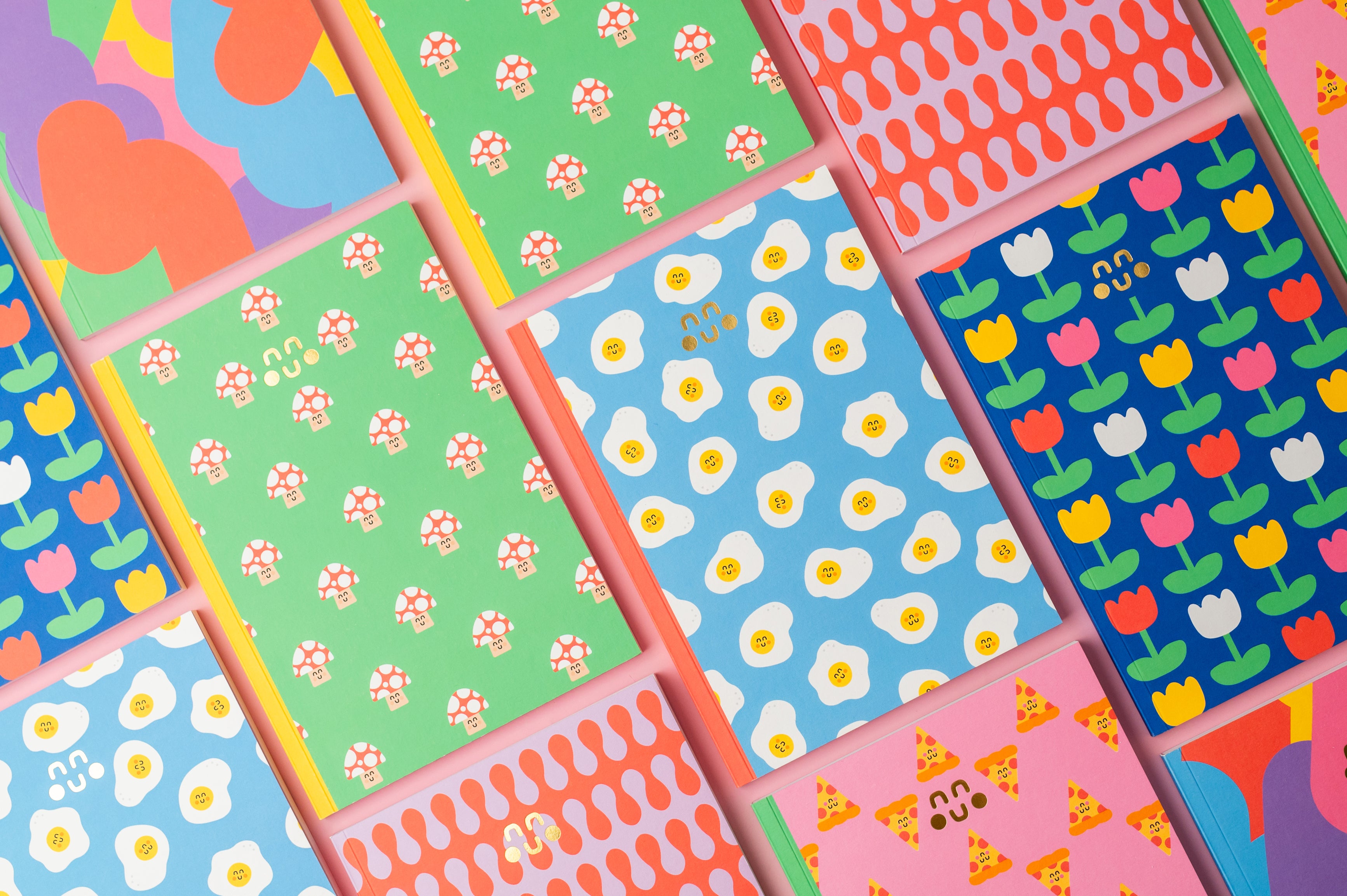 egg pattern, pizza pattern, mushroom pattern notebooks on a pink background