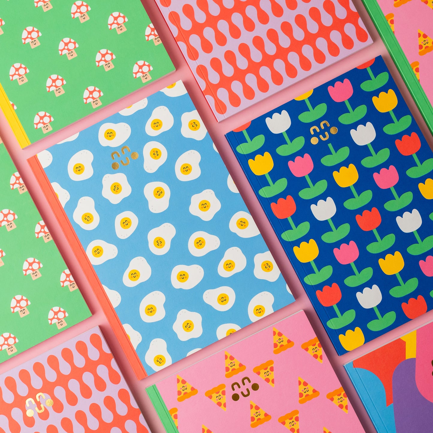 egg pattern, pizza pattern, mushroom pattern notebooks on a pink background
