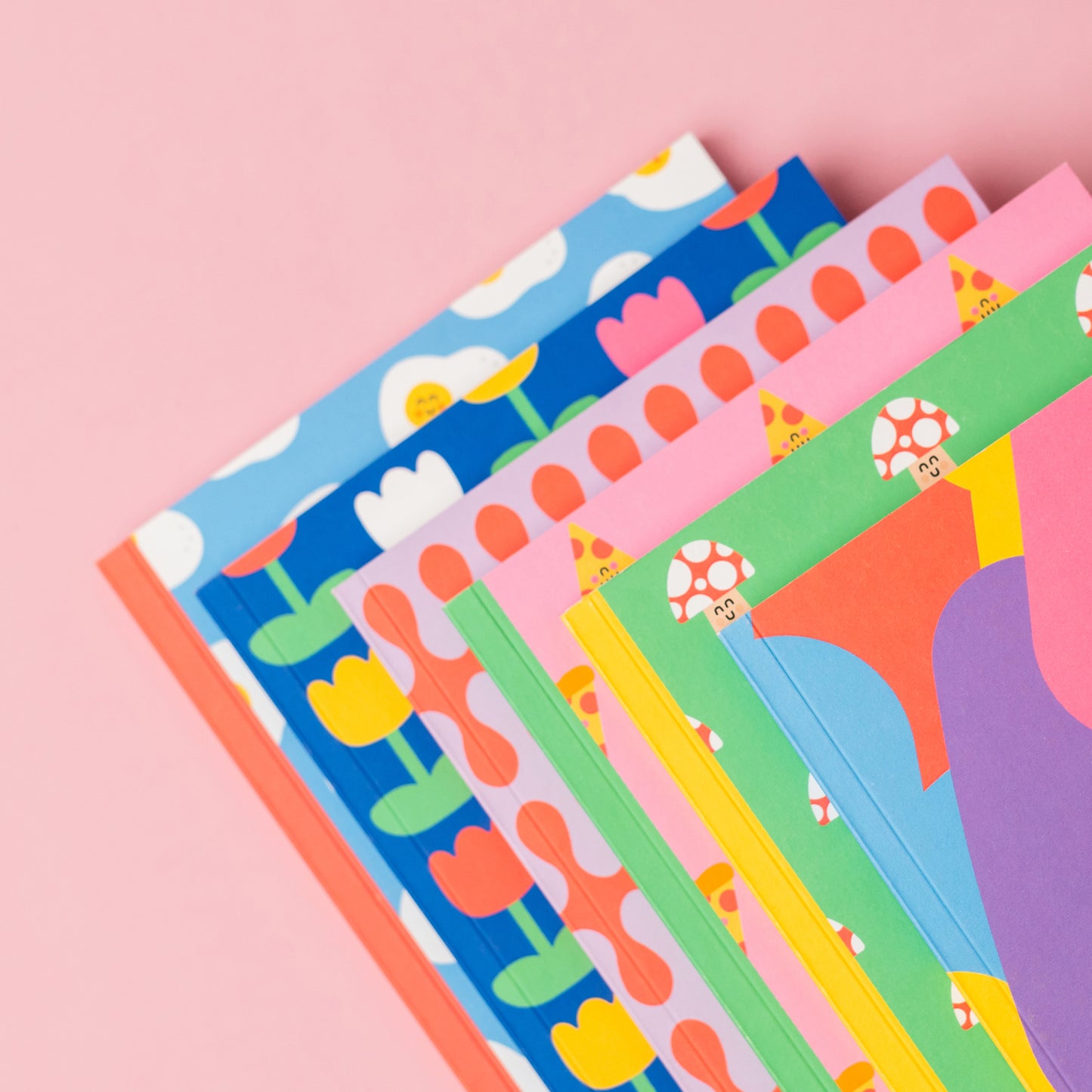A set of colorful notebooks on a pink background