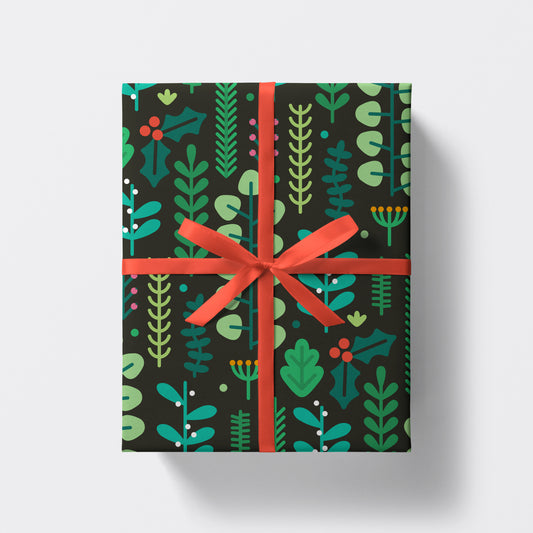 A Botanical gift wrap adorned with green leaves and tied elegantly with a red ribbon, from Studio Boketto.