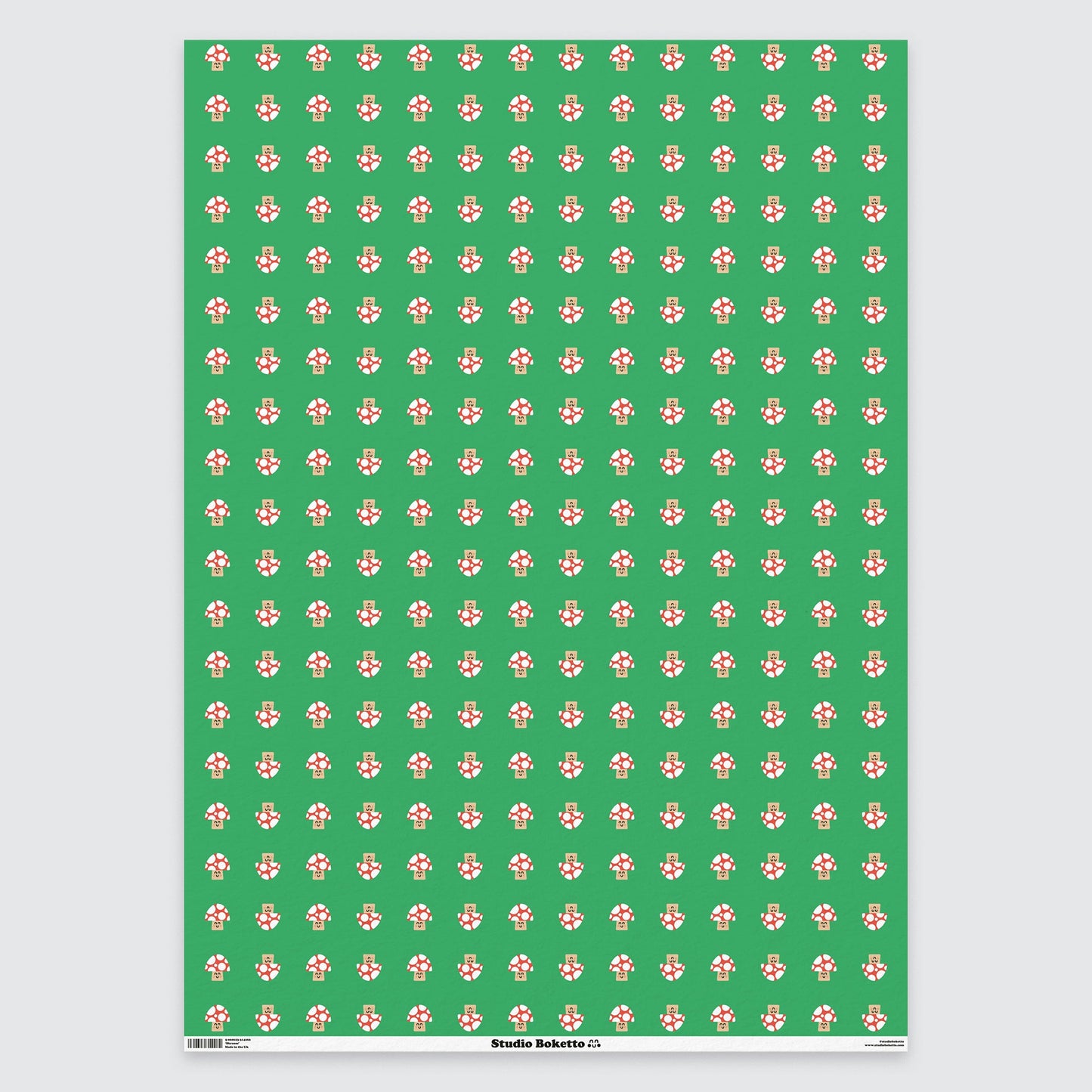 a flat sheet of wrapping paper with a cute red and white mushroom all over print pattern on a green background 