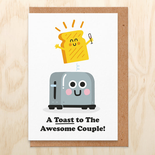 Wedding card with an illustration of a toaster and a smiling piece of toast holding a champagne glass popping out. It reads a toast to the awesome couple!