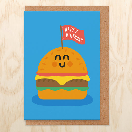 Birthday card with a bright blue background and an illustration of a burger with a flag in that says happy birthday.