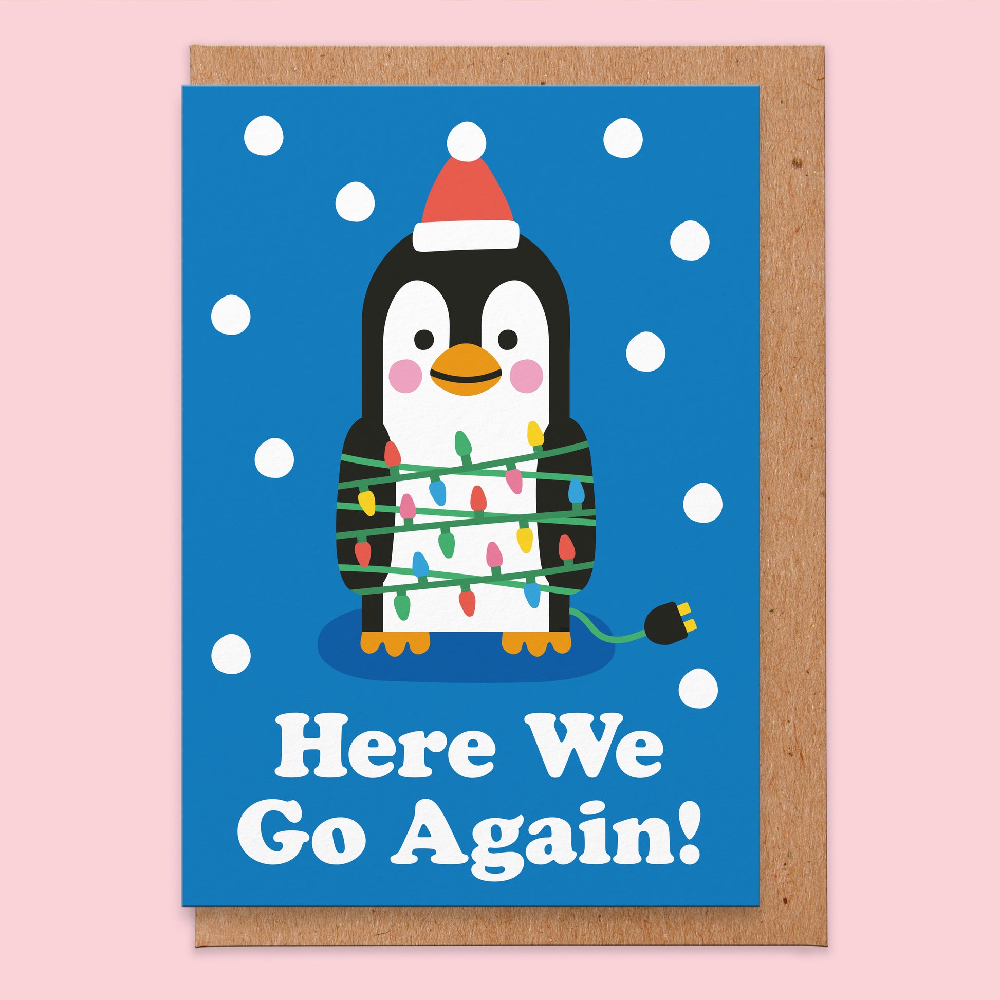 Christmas card that reads here we go again! With an illustration of a penguin with lots of fairy lights wrapped around it.