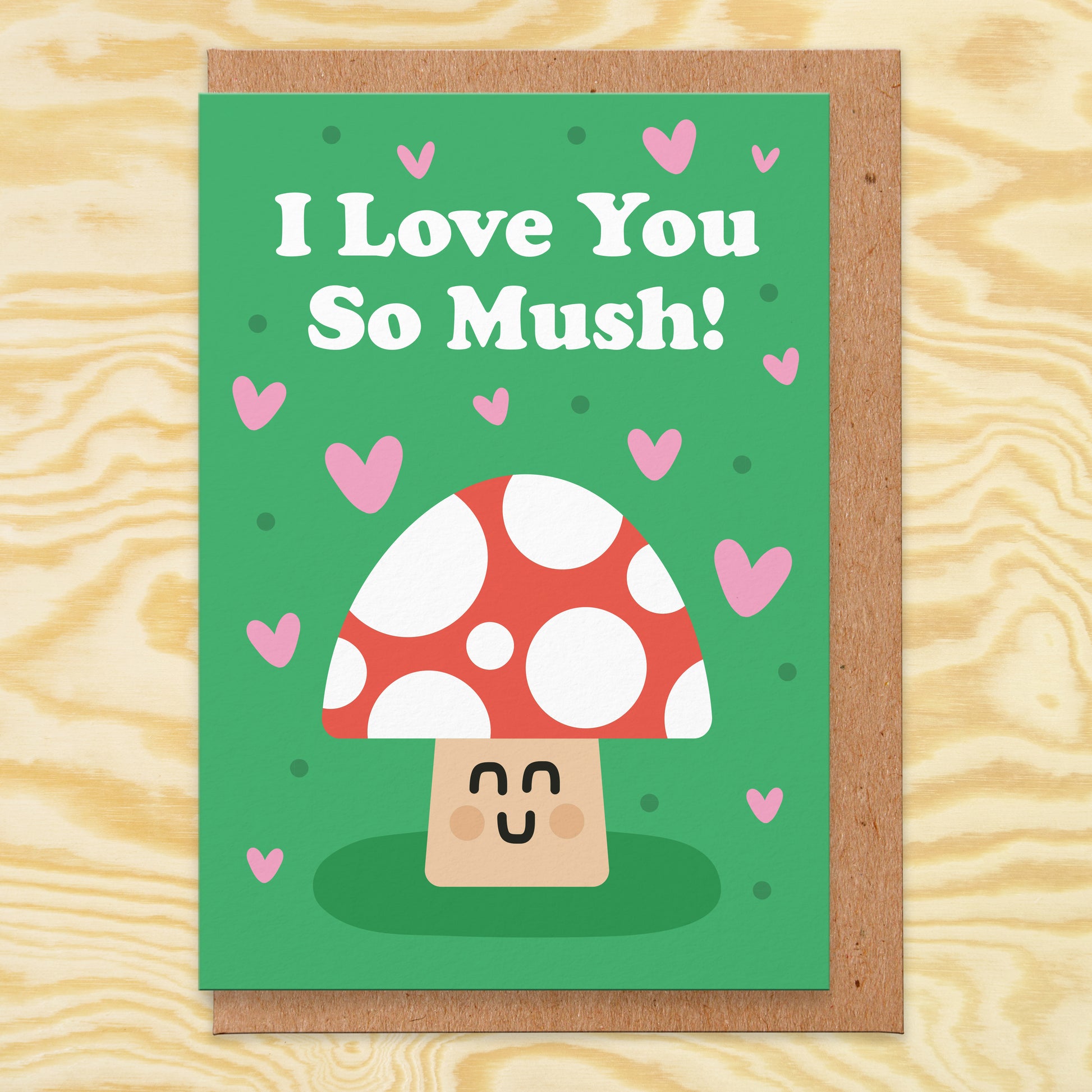 Love card with an illustration of a mushroom on a green background with pink hearts all over and it reads I love you so mush!