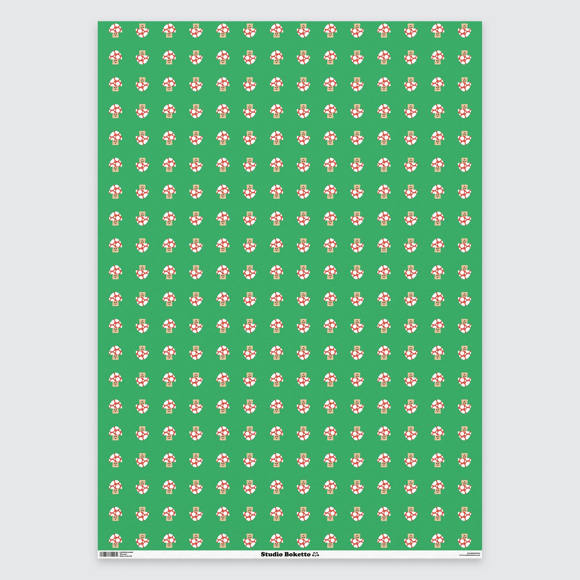 a flat sheet of wrapping paper with a cute red and white mushroom all over print pattern on a green background 