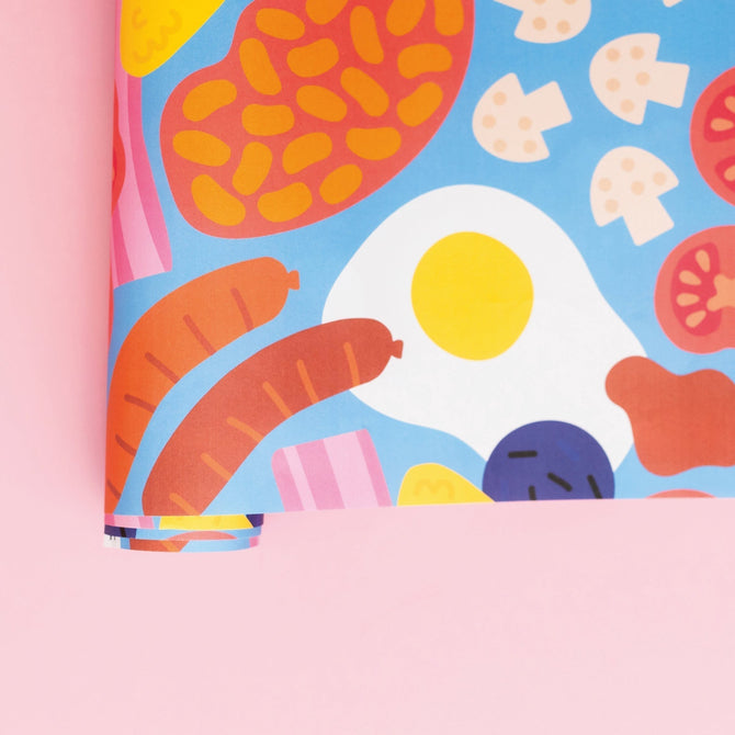 photograph of wrapping paper with the contents of a Full English breakfast on it including eggs bacon beans and sausages