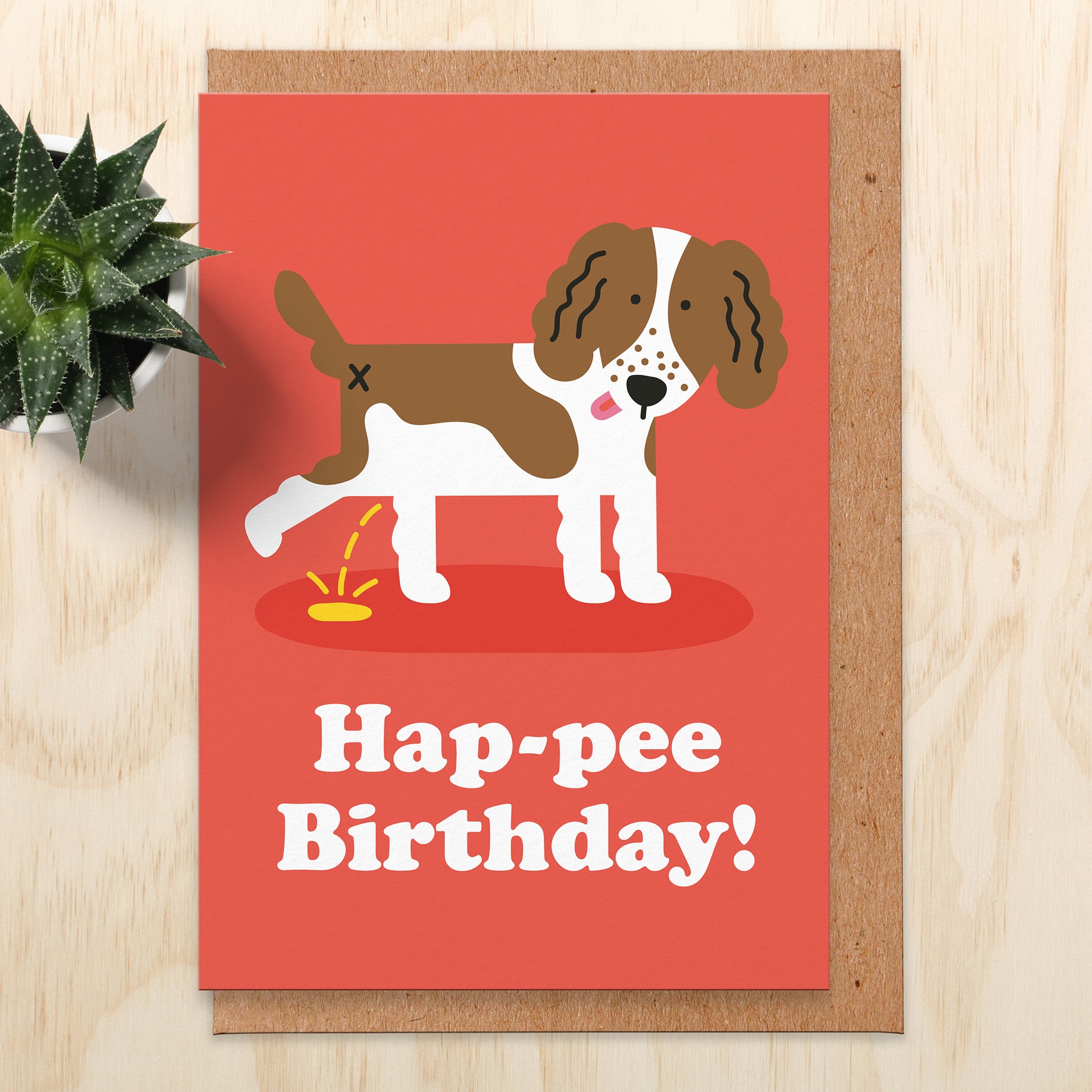 Birthday card with an illustration of a brown and white spaniel peeing. The background is red and the words read hap-pee birthday!