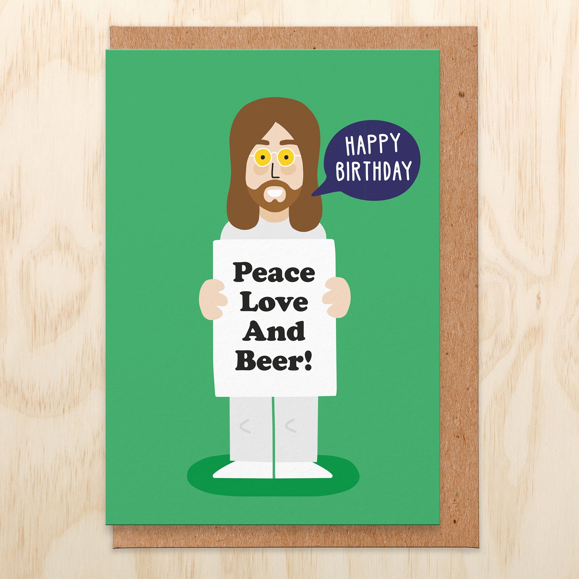 Green greetings card with an illustration of John holding a sign that says peace love and beer. There is a speech bubble saying happy birthday.