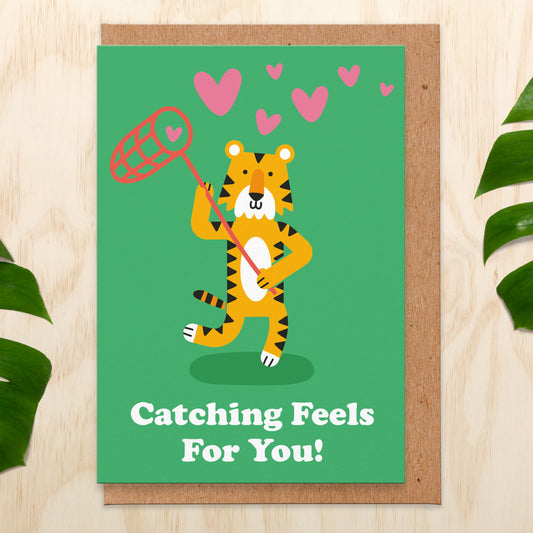 Love card with an illustration of a tiger with a net catching love hearts. It reads catching feels for you!