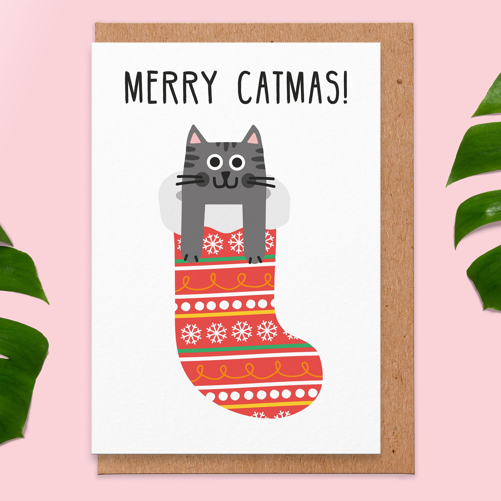 christmas card that reads merry catmas with an illustration of a grey cat popping out the top of a christmas stocking.