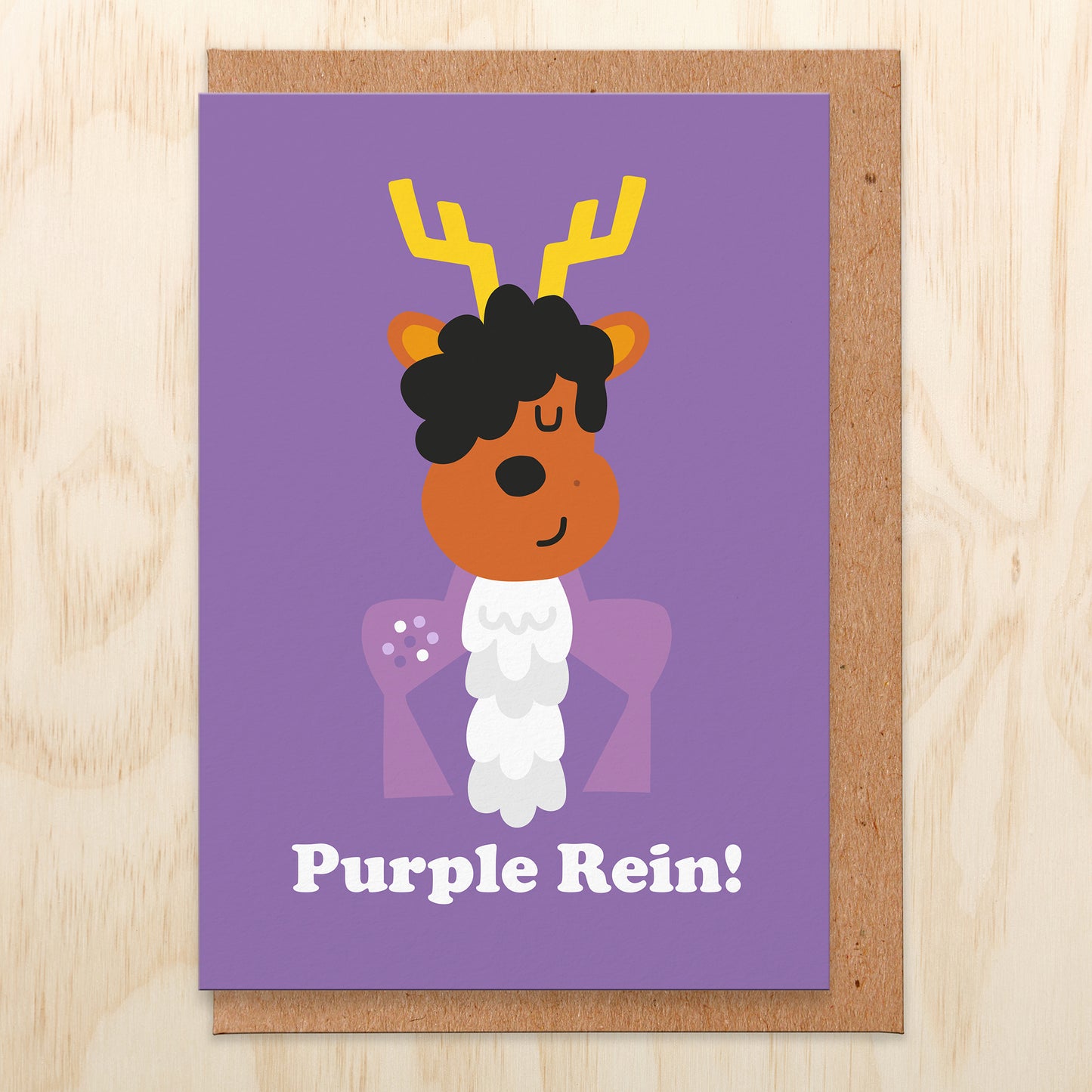 Christmas card with an illustration of a reindeer dressed as the purple rain singer. The card reads purple rein!