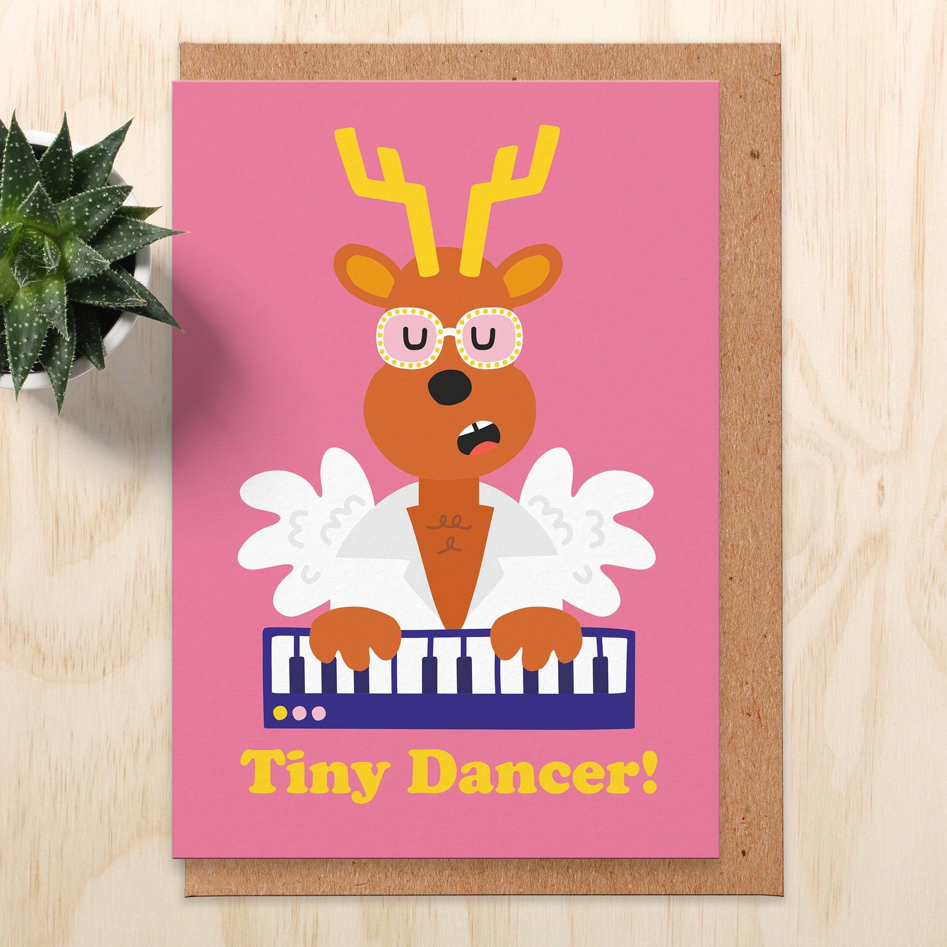 Christmas card with an illustration of reindeer dressed as tiny dancer singer and playing the piano. The test reads tiny dancer!